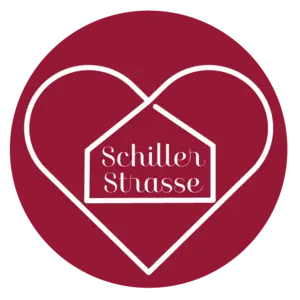 Logo Schillerstraße: dunkelroter Kreis, darin weiße Umrisse eines Herzens. Im Herz Umriss eines Hauses mit dem Wort Schillerstraße.
