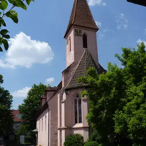 St. Lorenz Oberasbach Blick in den Pfarrhor von St. Lorenz mit dem Magnolienbaum im Vordergrun und dem rosfarbenen Kirchegebäude im HIntergrund